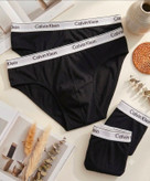شورتهای اسلیپ مردانه مشکی رنگ با کش پهن سفید Calvin Klein به همراه چیدمان هنری مجله و المانهای دکوراتیو