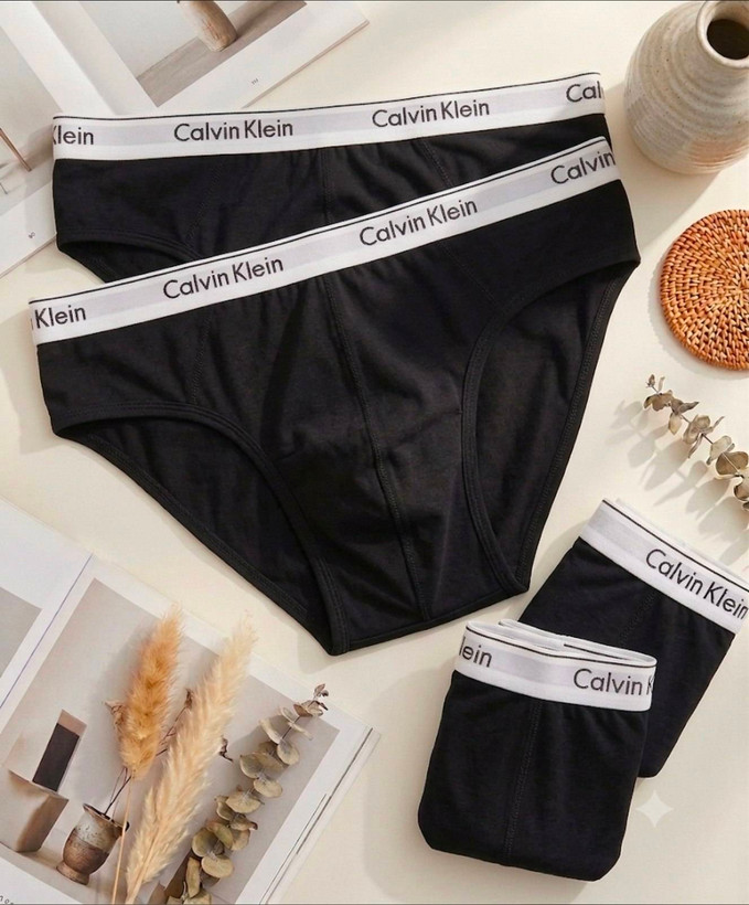 شورتهای اسلیپ مردانه مشکی رنگ با کش پهن سفید Calvin Klein به همراه چیدمان هنری مجله و المانهای دکوراتیو